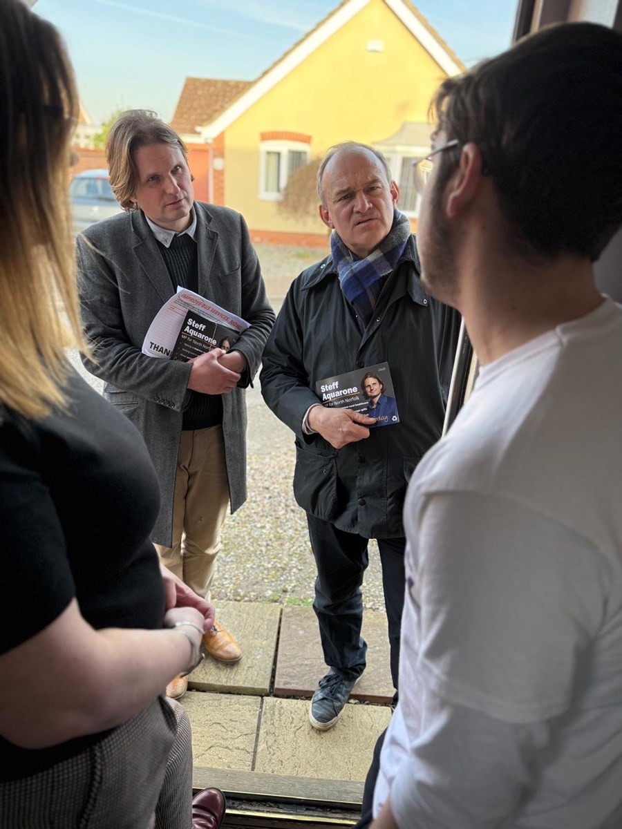 Emily and Joel are standing in the doorway, meeting politicians Steff Aquerone and Ed Davey
