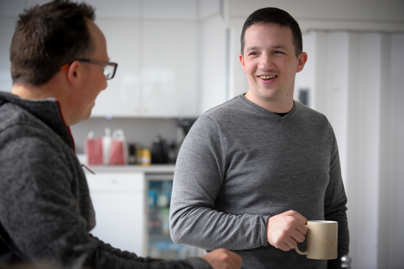 Two men with mugs chatting